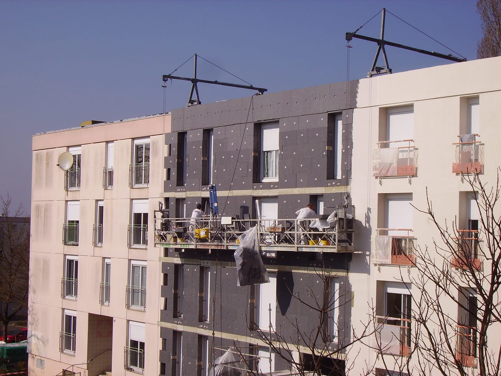 Illustrative image: insulation boards being fixed to the facade of an apartment building during renovation.